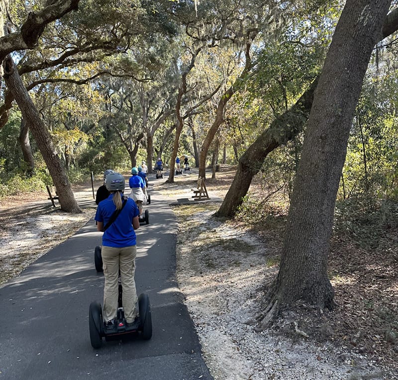 Group of people riding Segways on a shaded forest path