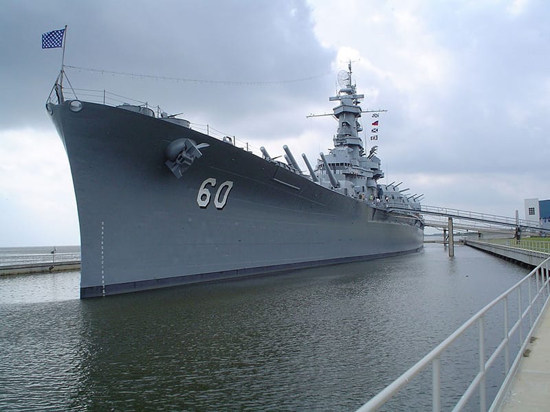 Large battleship number 60, displayed in a maritime museum, under cloudy skies