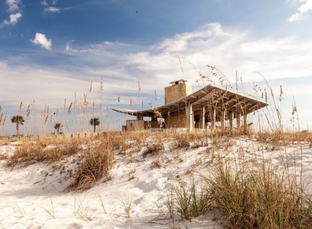 Beachside building with observation tower on a sandy dune under a cloudy sky