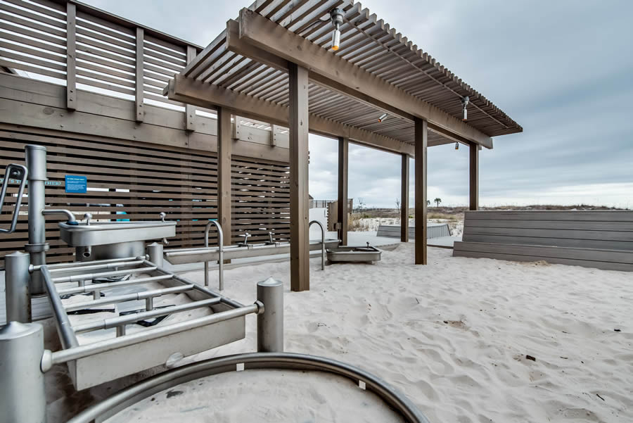 Outdoor beach gym with accessible equipment under a wooden pergola on a sandy ground
