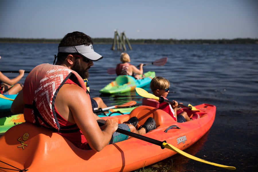 Adult and children kayaking together on a lake on a sunny day