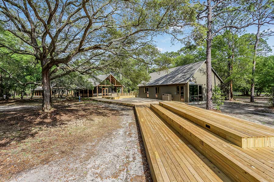 Wooden cabins in a park with large trees and a newly constructed deck